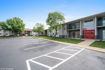 A parking lot in front of a building with a red door.